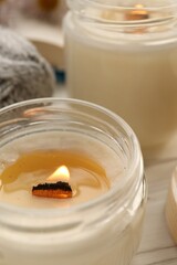 Burning scented candles on white wooden table, closeup