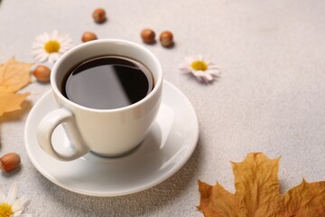 Composition with cup of hot drink and autumn leaves on light grey textured table, closeup