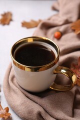 Composition with cup of hot drink and autumn leaves on light grey textured table, closeup