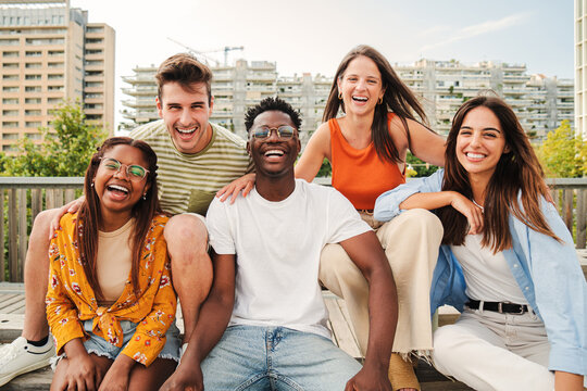 Happy multiracial young people smiling together looking at camera, five teenage friends having fun and laughing taking picture outside on city street. Lifestyle Concept. High quality photo