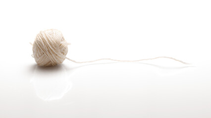 A ball of white woolen threads on a white background with a shadow. Side view.