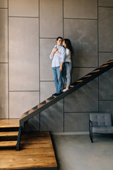 Young couple husband and wife at home sitting on the stairs hugging