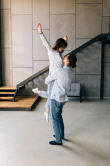 Young man lifting holding woman in hands standing starting living together