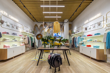 The interior of a modern clothing store with an original design. Shelves with clothes around the...