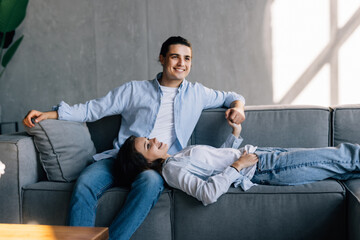 Young family of two relaxing on sofa at home on weekend