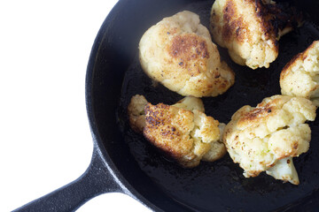 Cauliflower fried, in a cast iron frying pan with olive oil. Isolated on a white background