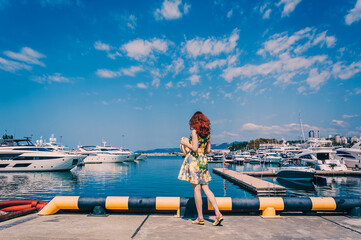 Young girl is looking at the yachts in the Marine Station in Sochi. Summer Vacation. Destination.