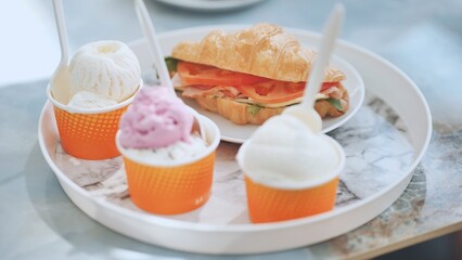 Ice cream and croissant with meat on the plate at the cafe.