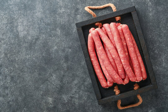 Meat beef sausages. Raw barbecue sausages with spices, vegetables and ingredients for cooking on black background. Top view. Copy space. Oktoberfest menu concept.