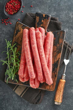 Meat beef sausages. Raw barbecue sausages with spices, vegetables and ingredients for cooking on black background. Top view. Copy space. Oktoberfest menu concept.