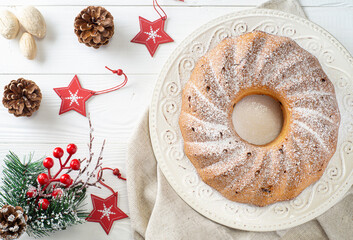 Traditional Xmas bundt cake with raisins, dried cherries, cranberry and sugar powder on a white plate