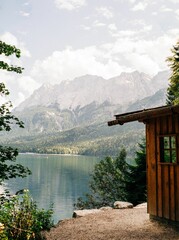 Obraz premium Wooden cabin near the clear lake with a mountain landscape view