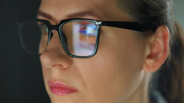 Woman in glasses looking on the monitor and working with charts at night