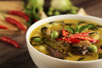 Thai food chicken green curry with coconut curry on dark wooden background.