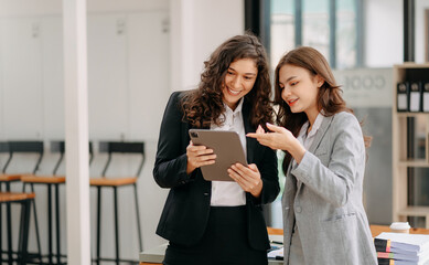 Businesswomen work and discuss their business plans. A Human employee explains and shows her colleague the results paper in modern office..
