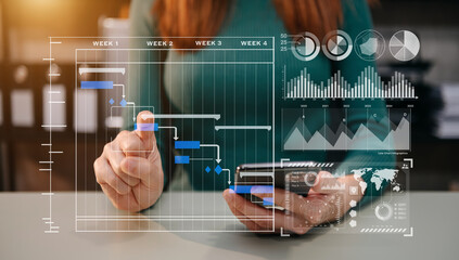 Businessman hand Project manager working and update tasks and Gantt chart scheduling virtual diagram.with smart phone, tablet and laptop in office..