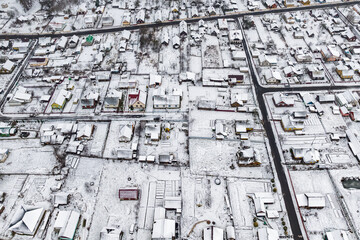aerial panoramic winter view of village with houses, barns and gravel road with snow