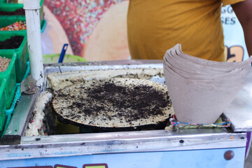 making street food using an iron plate that is heated and rotated, on which the dough is placed on the plate so that it dries.