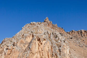 A view of a hill with steep rocks and a blue sky 