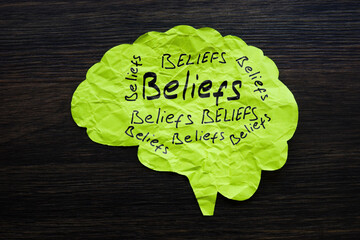 Paper brain with handwritten words beliefs. Bias concept.