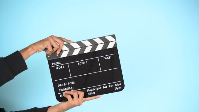Hand is holding clapper board or clapperboard or movie slate, used in film production and cinema ,movies industry isolated over color background.