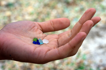 Woman hands holding colored crystals eroded by the sea in the beach of the crystals in the silleiro cape in Pontevedra
