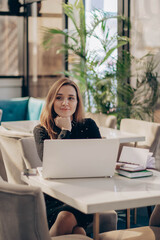 Shot of pretty happy young entrepreneur woman working with laptop sitting in the office.
co-working or modern office or restaurant. 