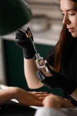 Selective focus on cosmetic bottle with pipette in hands of woman beautician.