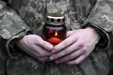 Ukrainian seviceman holds a candle. Candle in hands of Soldier