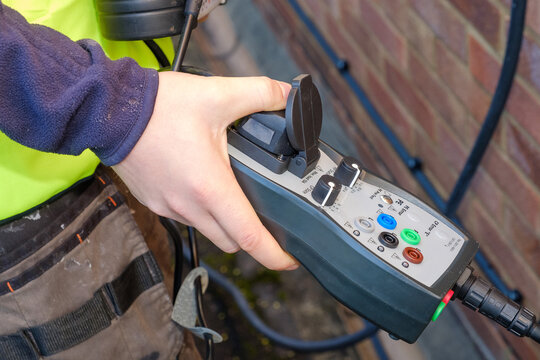 Close-up of electrician using electrical test equipment to check outdoor car charger installation