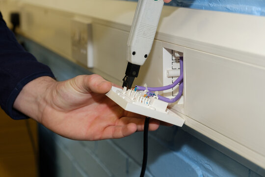 Close-up of electrician testing wiring in UK data socket in office