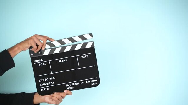 Hand is holding clapper board or clapperboard or movie slate, used in film production and cinema ,movies industry isolated over color background.