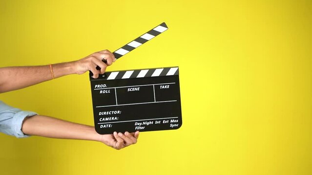 Hand is holding clapper board or clapperboard or movie slate, used in film production and cinema ,movies industry isolated over color background.