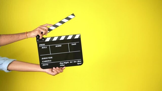 Hand is holding clapper board or clapperboard or movie slate, used in film production and cinema ,movies industry isolated over color background.
