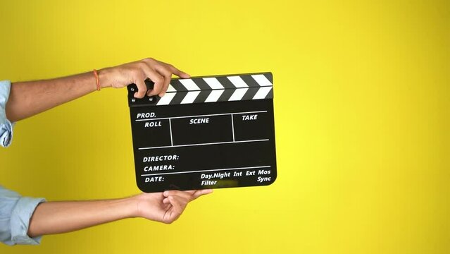Hand is holding clapper board or clapperboard or movie slate, used in film production and cinema ,movies industry isolated over color background.