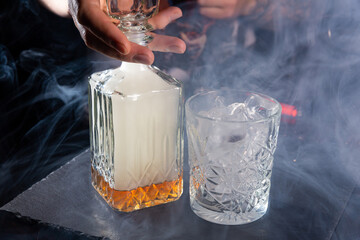 The bartender mixes whiskey with smoke to give a special taste to the drink.