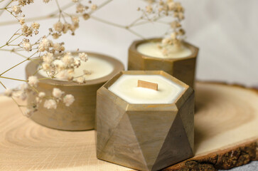 Scented candles in a flowerpot on a wooden stand. Soy wax candle and gypsophila sprig