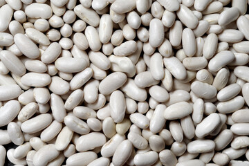 Healthy large raw husked white kidney beans scattered of evenly layer, view close-up
