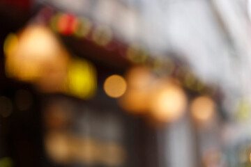 Blur background of European city street with bokeh of garlands, shop windows, cafe signboards
