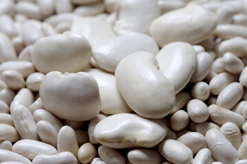 Healthy large raw husked white kidney beans scattered of evenly layer, view close-up
