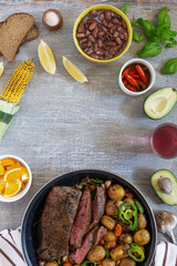 Large fried piece of ham meat in a pan with vegetables and spices, American lunch fried piece of meat and potatoes, beans in sauce and snacks, copy space for text