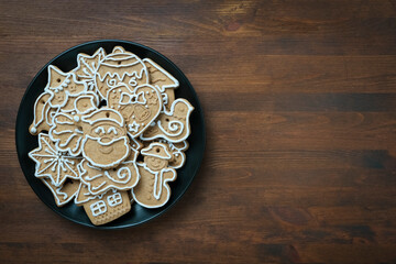 Christmas gingerbread cookies on a dark plate on a wooden background with copy space