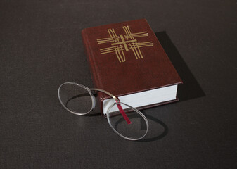 A reading pince-nez and a Christian prayer book - obrazy, fototapety, plakaty