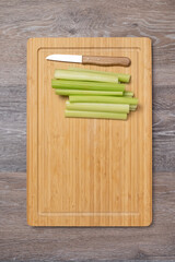 Stems of fresh juicy celery are sliced on a cutting board with copy space