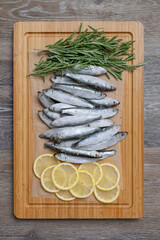 Frozen sprats on a kitchen board with lemons and rosemary