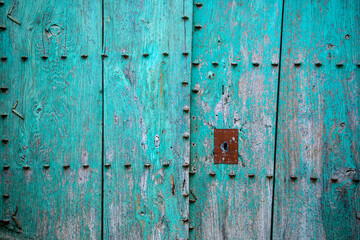 Old aged double leaf door with metal ornaments on bluish green painted natural wood