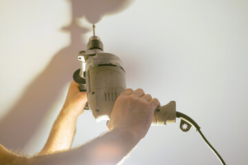 Drilling a hole in the ceiling with an electric drill