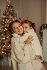 Happy New Year! family traditions. young mother and her daughter have fun at home near the Christmas tree and fireplace