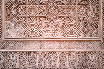 A moorish / Islamic pattern with symmetrical elements on an ancient monument. Backdrop for graphic resource or decorative copy space. Warm colours taken in summer.