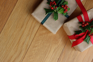 Naklejka na ściany i meble Two Christmas gifts with Holly decoration with red berries on a wooden background with copy space